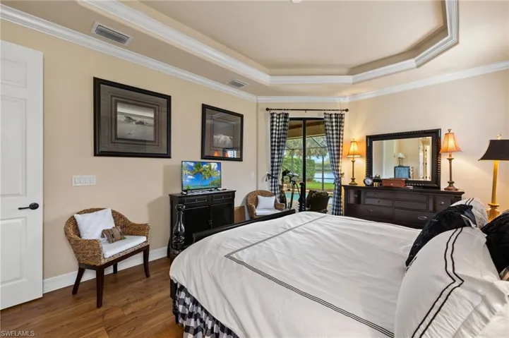 Bedroom featuring visible vents, a raised ceiling, baseboards, and wood finished floors