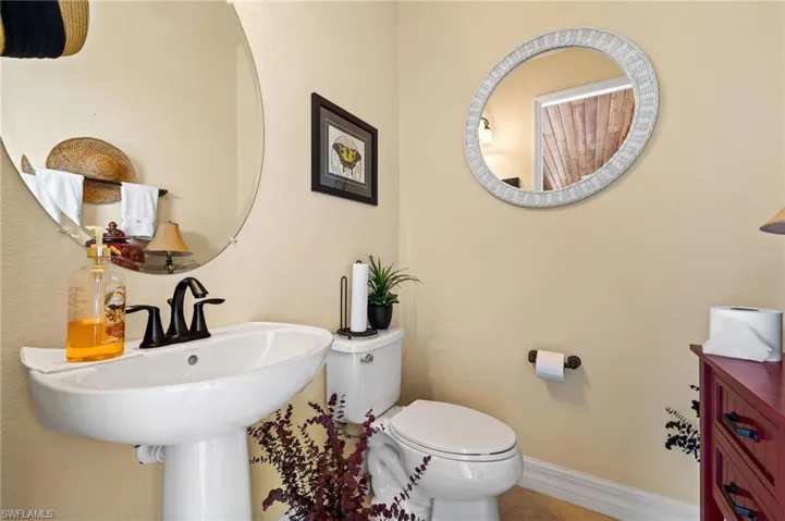 Bathroom featuring tile patterned flooring, toilet, baseboards, and a sink
