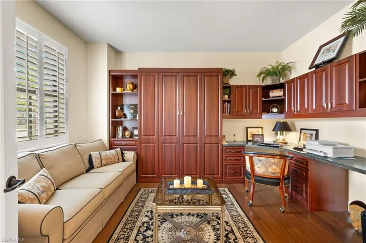 Office space with built in desk and dark wood-type flooring