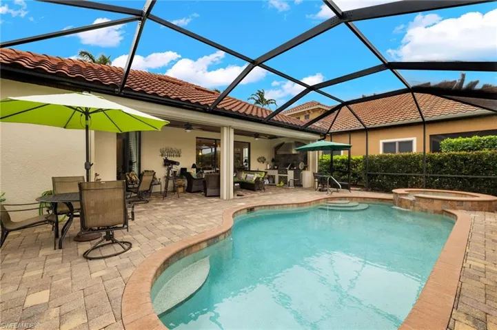View of pool with a ceiling fan, a pool with connected hot tub, glass enclosure, outdoor dining area, and a patio area