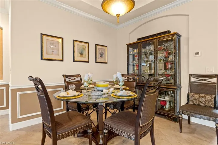Dining space featuring crown molding, light tile patterned floors, and a wainscoted wall