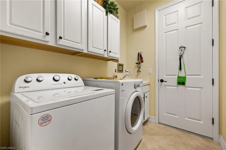 Laundry room with light tile patterned flooring, cabinet space, and separate washer and dryer