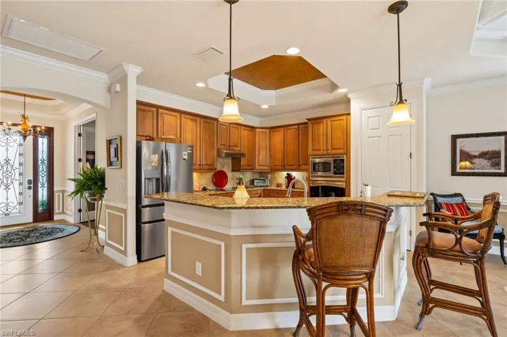 Kitchen with a tray ceiling, brown cabinets, appliances with stainless steel finishes, and under cabinet range hood
