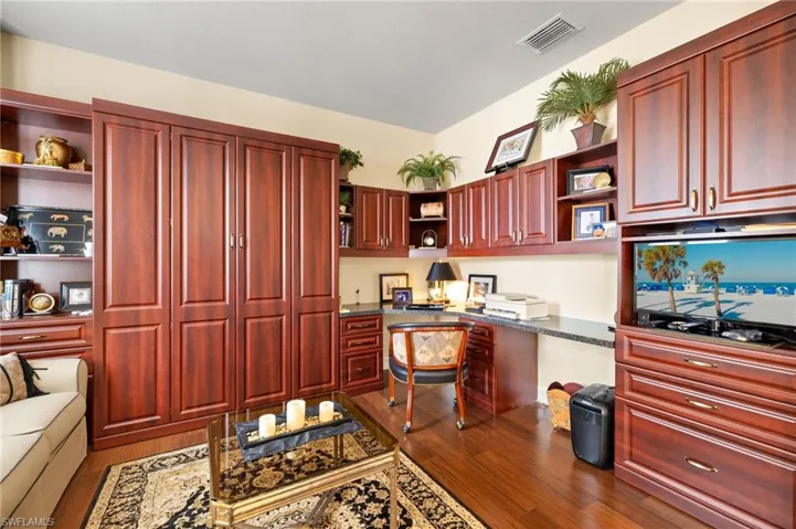Office area featuring visible vents, wood finished floors, and built in desk