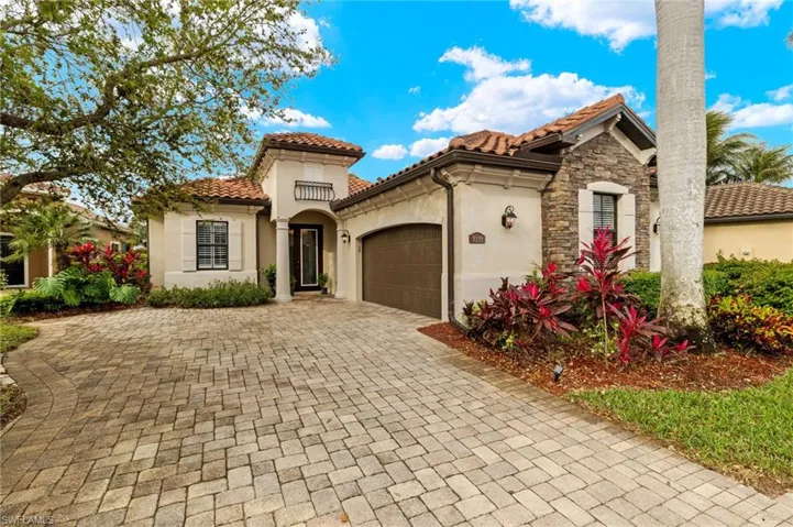 Mediterranean / spanish-style house with stucco siding, stone siding, an attached garage, and a tiled roof