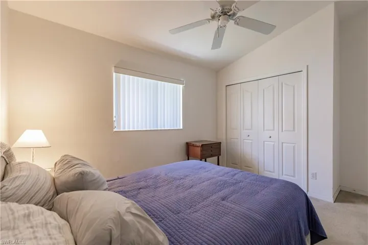 Bedroom featuring ceiling fan, carpet, a closet, and lofted ceiling