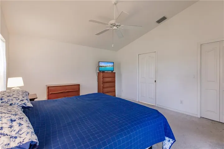 Carpeted bedroom with ceiling fan and vaulted ceiling