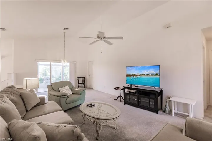Living room featuring light colored carpet, ceiling fan, and high vaulted ceiling