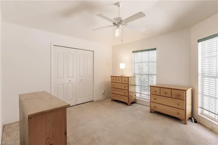 Carpeted bedroom featuring ceiling fan and a closet