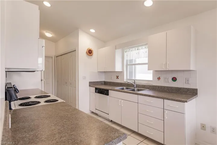 Kitchen featuring light tile patterned flooring, white cabinetry, white appliances, backsplash, and sink