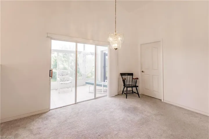 Spare room with a notable chandelier, light colored carpet, and high vaulted ceiling