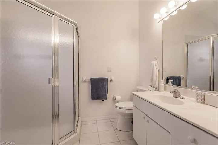 Bathroom with vanity, tile patterned floors, walk in shower, and toilet