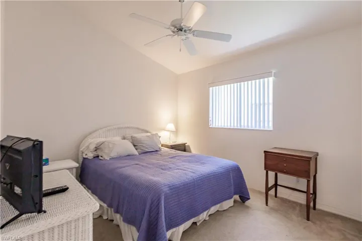 Carpeted bedroom with lofted ceiling and ceiling fan
