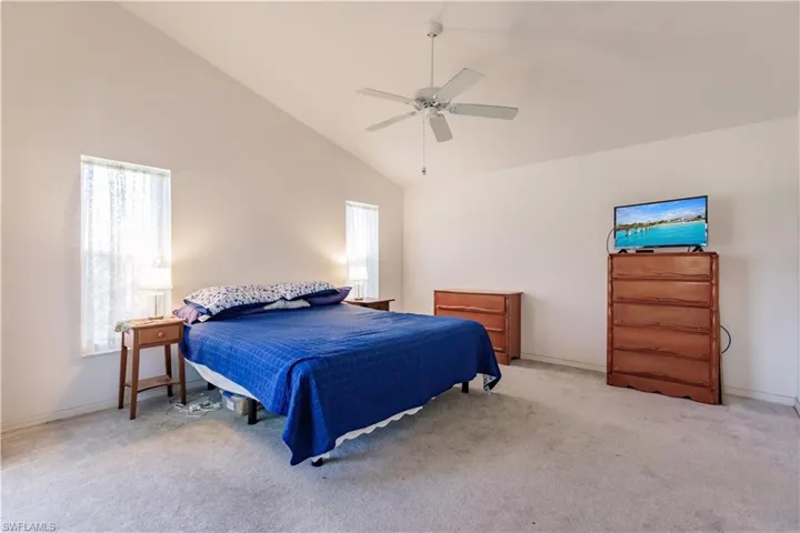Bedroom featuring light carpet, high vaulted ceiling, and ceiling fan