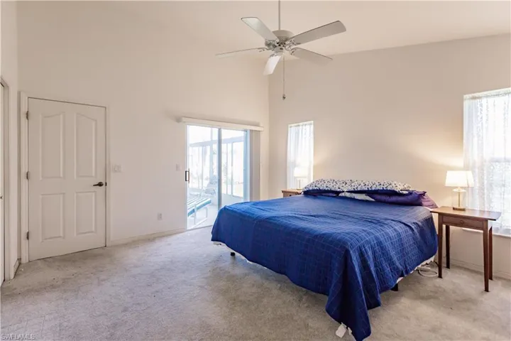 Bedroom with high vaulted ceiling, access to outside, light carpet, and ceiling fan
