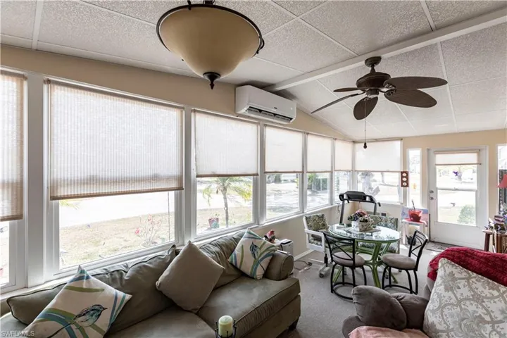 Sunroom featuring vaulted ceiling, carpet, and an AC wall unit