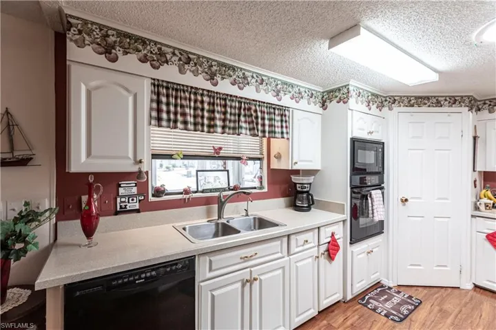 Kitchen featuring black appliances, a textured ceiling, a sink, and light countertops