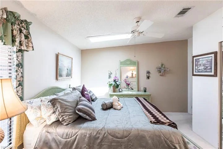 Bedroom with a textured ceiling, visible vents, and a ceiling fan