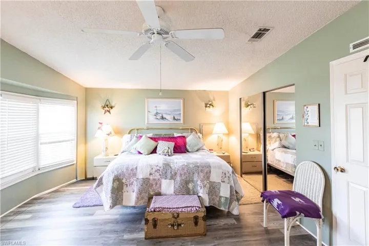 Bedroom featuring visible vents, wood finished floors, a textured ceiling, and vaulted ceiling