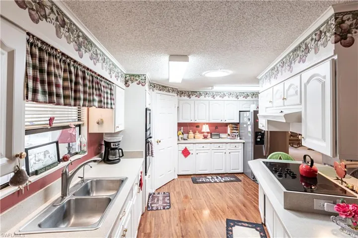 Kitchen featuring a textured ceiling, light countertops, white cabinets, and a sink
