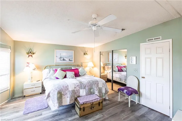 Bedroom featuring a closet, wood finished floors, visible vents, a textured ceiling, and lofted ceiling