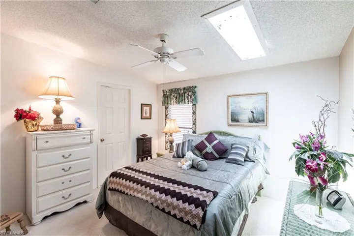 Bedroom featuring light colored carpet, a ceiling fan, and a textured ceiling