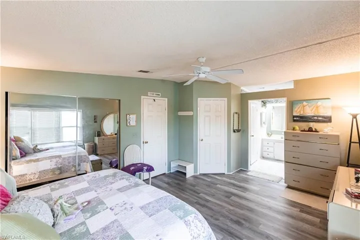Bedroom with a textured ceiling, visible vents, and wood finished floors