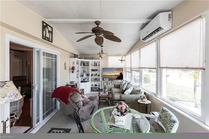 Sunroom with beam ceiling, a ceiling fan, french doors, and a wall mounted AC