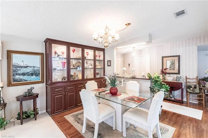 Dining space with a textured ceiling, an inviting chandelier, wood finished floors, and visible vents