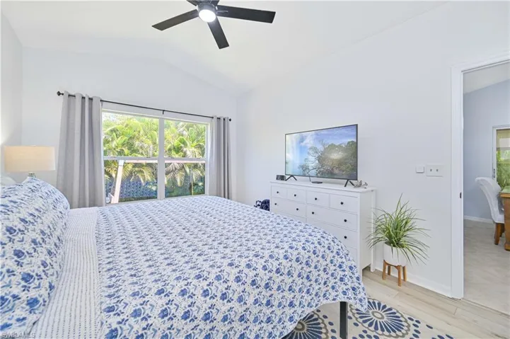 Bedroom with baseboards, a ceiling fan, vaulted ceiling, and light wood-type flooring