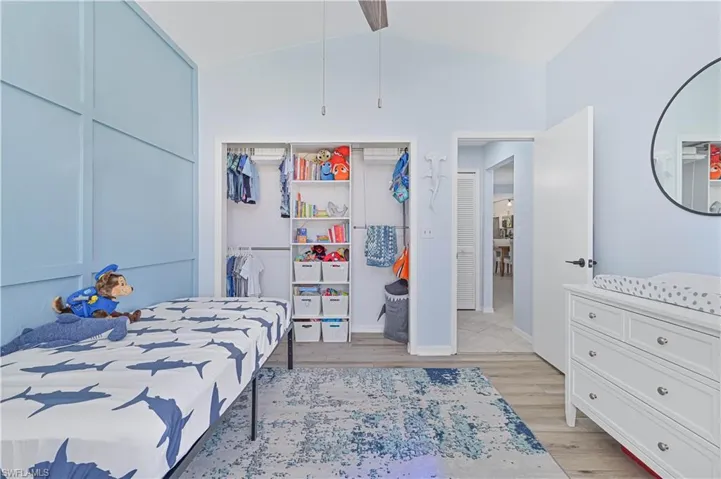 Bedroom with a closet, baseboards, lofted ceiling, and light wood-type flooring