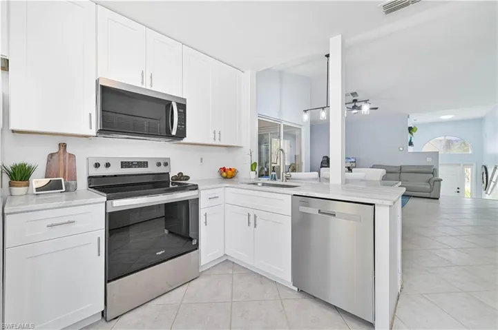 Kitchen featuring appliances with stainless steel finishes, a sink, light countertops, light tile patterned floors, and visible vents