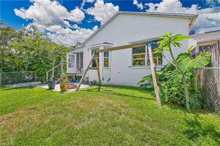 Back of property featuring a fenced backyard, stucco siding, a lawn, and stairway