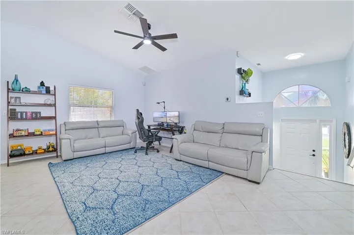 Living room with visible vents, a ceiling fan, light tile patterned floors, and high vaulted ceiling