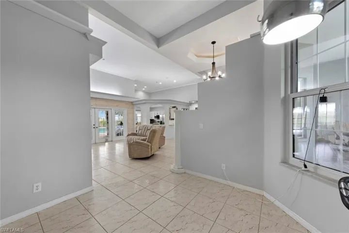 Living room featuring a raised ceiling, an inviting chandelier, and french doors