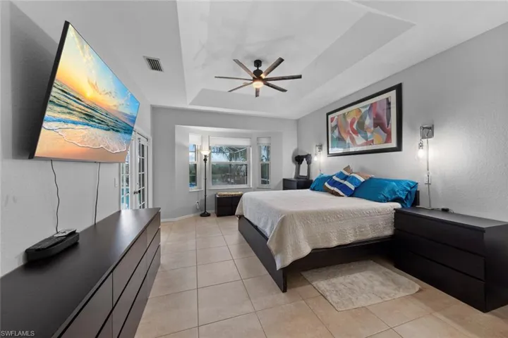 Tiled bedroom featuring a tray ceiling and ceiling fan