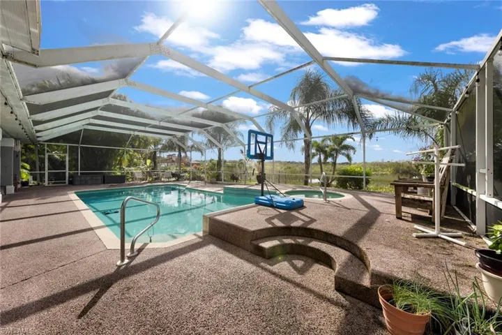 View of pool featuring glass enclosure, a hot tub, and a patio area