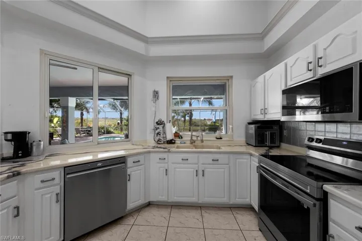 Kitchen with stainless steel appliances, white cabinets, and a healthy amount of sunlight