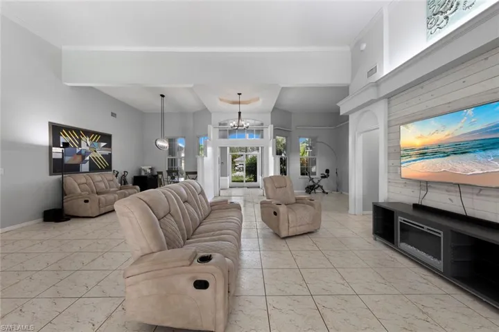 Tiled living room featuring an inviting chandelier and crown molding