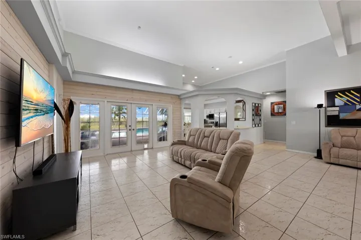 Living room featuring ornamental molding, light tile patterned floors, and french doors
