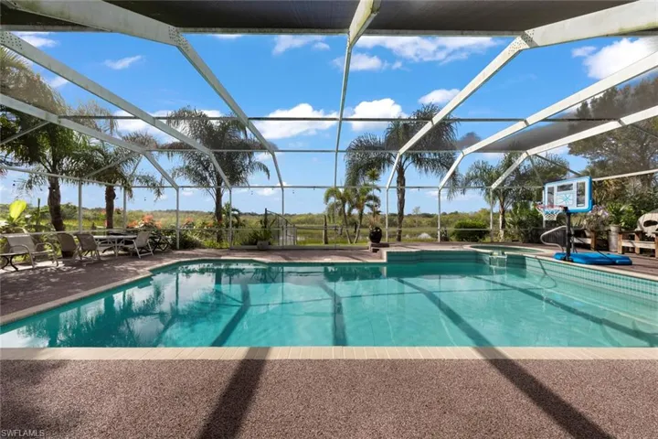 View of swimming pool featuring glass enclosure and a patio