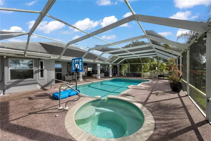 View of pool featuring a patio, glass enclosure, and an in ground hot tub