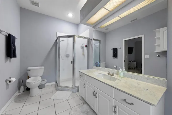 Bathroom featuring a shower with door, vanity, and toilet