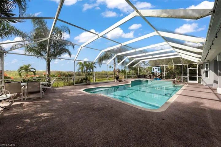 View of swimming pool featuring glass enclosure and a patio area