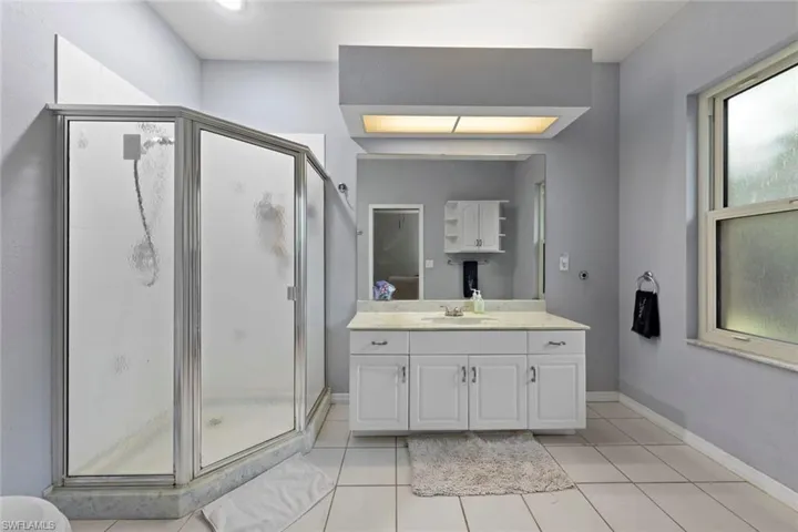 Bathroom with vanity, tile patterned flooring, and an enclosed shower