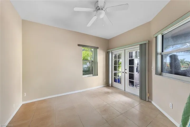 Empty room featuring light tile patterned floors, ceiling fan, and french doors