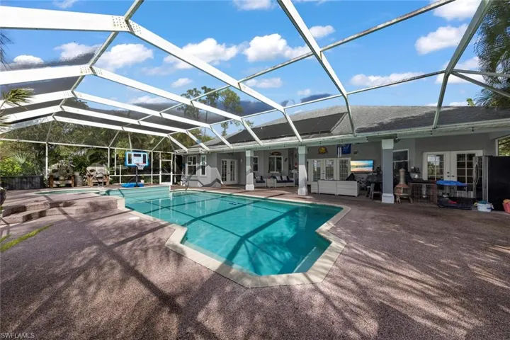 View of swimming pool with french doors, glass enclosure, and a patio area