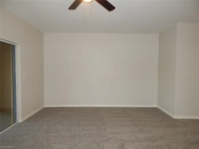 Carpeted living room with ceiling fan and baseboards