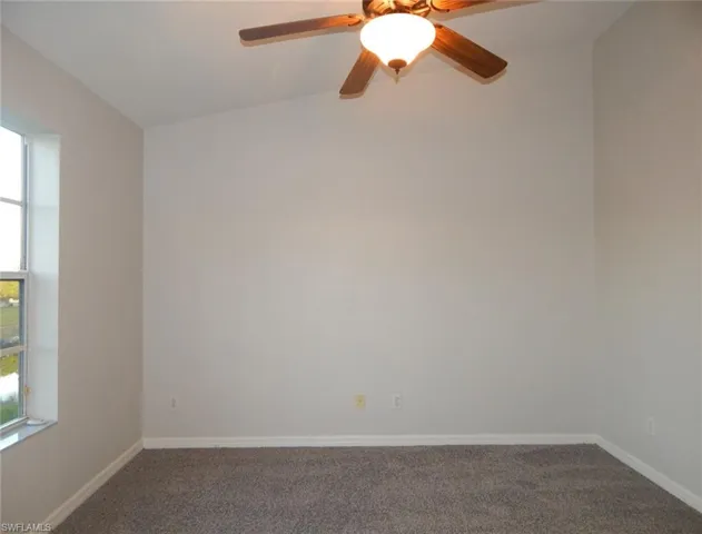 Master bedroom featuring plenty of natural light, a ceiling fan, dark carpet, and lofted ceiling