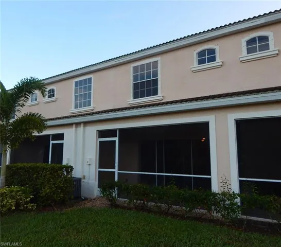 Back of property featuring stucco siding, a sunroom, and a tile roof